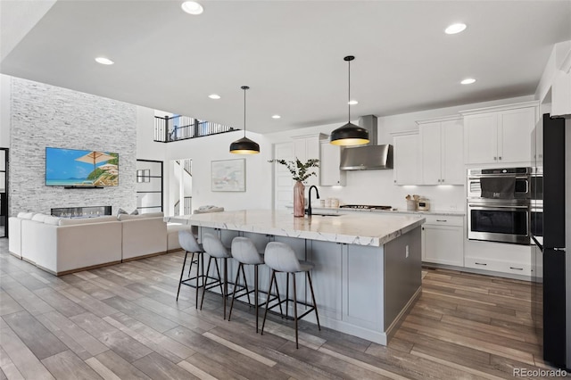 kitchen featuring wood finished floors, stainless steel double oven, cooktop, and freestanding refrigerator