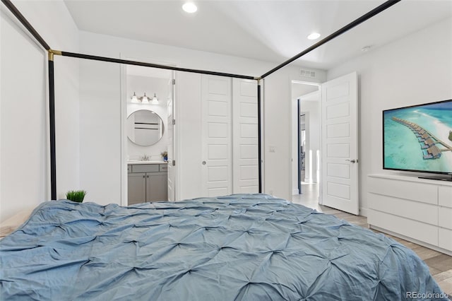 bedroom with recessed lighting, visible vents, light wood-style floors, connected bathroom, and a sink