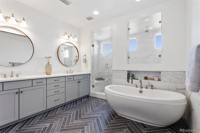 full bathroom with double vanity, a soaking tub, a shower stall, and a sink