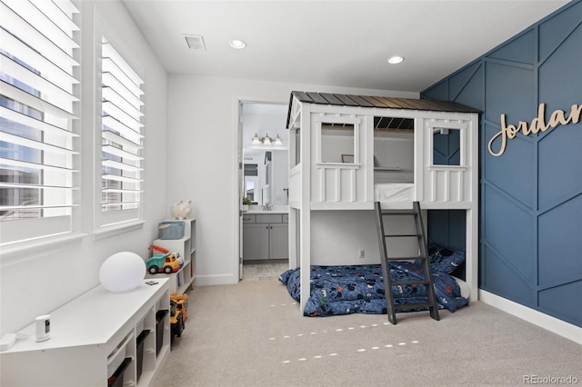 carpeted bedroom featuring visible vents, ensuite bath, a decorative wall, a sink, and recessed lighting