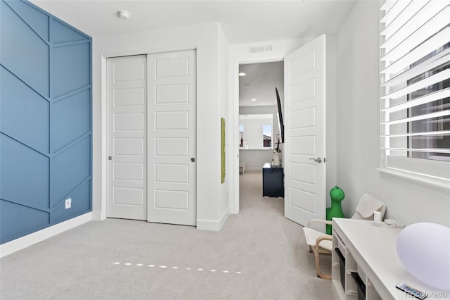 bedroom with a closet, light carpet, visible vents, and baseboards