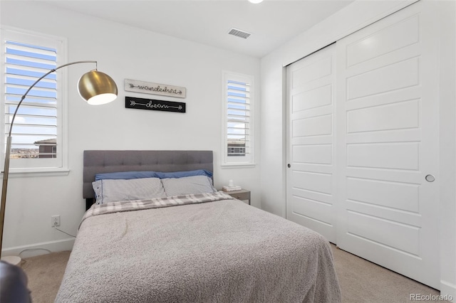 bedroom featuring multiple windows, a closet, and light colored carpet