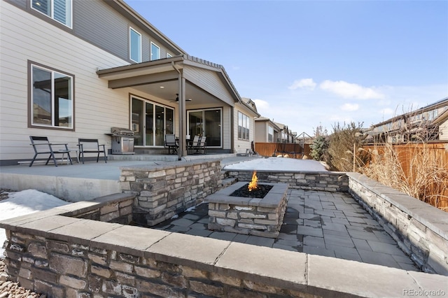 view of patio featuring fence, ceiling fan, a fire pit, and grilling area