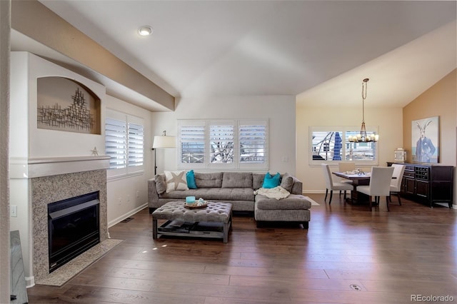 living room with a chandelier, dark wood-type flooring, baseboards, vaulted ceiling, and a tiled fireplace