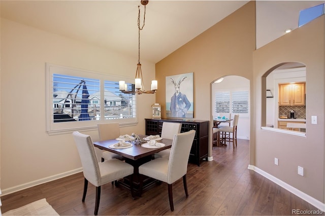 dining space with high vaulted ceiling, dark wood finished floors, and baseboards