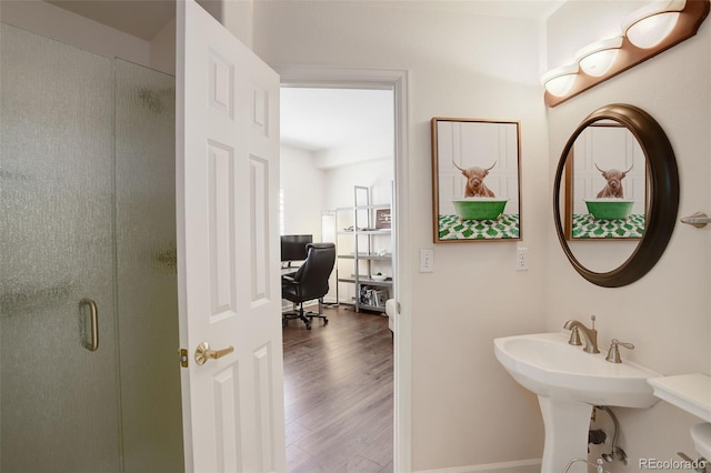 full bathroom with a stall shower, a sink, and wood finished floors