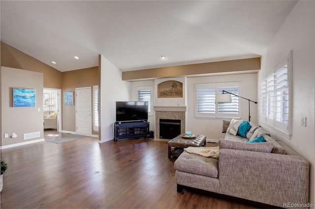 living room with a wealth of natural light, dark wood finished floors, visible vents, and vaulted ceiling