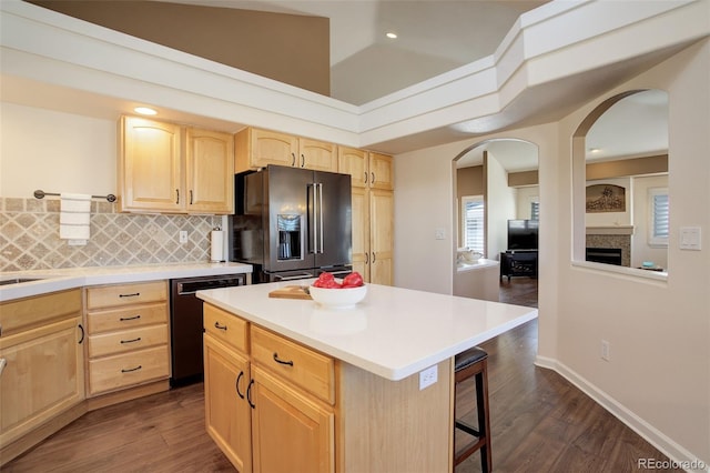 kitchen featuring black dishwasher, high quality fridge, light brown cabinets, and a breakfast bar