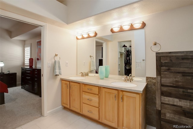 full bathroom featuring double vanity, a spacious closet, tile patterned flooring, and a sink