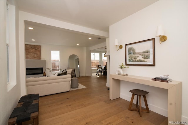 living room featuring recessed lighting, light wood-type flooring, baseboards, and a glass covered fireplace