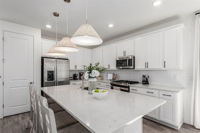 15774 W Girard Ave, Morrison, CO 80465 - kitchen featuring white cabinetry, a kitchen island with sink, wood finished floors, appliances with stainless steel finishes, and hanging light fixtures
