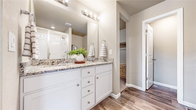 1933 Villageview Ln, Castle Rock, CO 80104 - full bathroom featuring wood finished floors, a shower stall, double vanity, a walk in closet, and baseboards