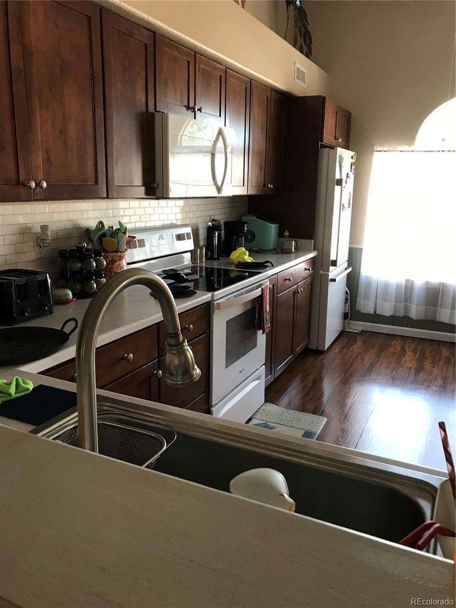838 Edna Ln, Pueblo, CO 81005 - kitchen featuring white appliances, dark wood-type flooring, tasteful backsplash, and dark brown cabinetry