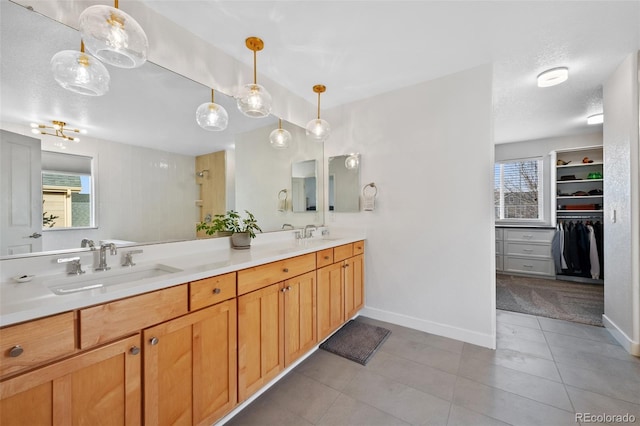 bathroom featuring double vanity, baseboards, a sink, and tile patterned floors