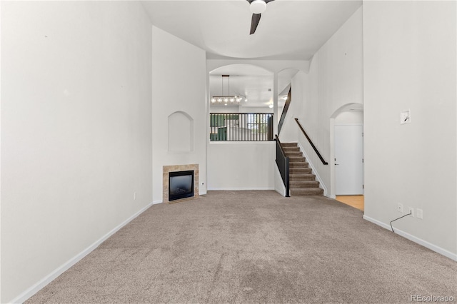 10578 E Jewell Ave, Aurora, CO 80012 - unfurnished living room with carpet floors, a tiled fireplace, ceiling fan, and stairs