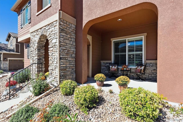 view of exterior entry with stone siding and stucco siding