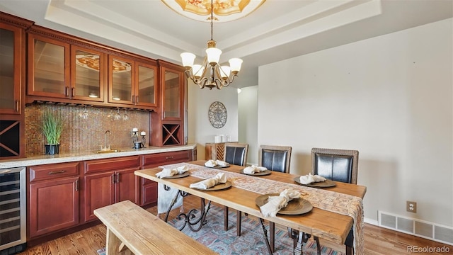 11818 Rio Secco Rd, Peyton, CO 80831 - dining area featuring beverage cooler, a chandelier, a tray ceiling, and bar with sink