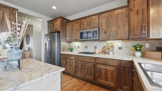 11818 Rio Secco Rd, Peyton, CO 80831 - kitchen featuring appliances with stainless steel finishes, light wood-style flooring, decorative backsplash, recessed lighting, and a sink