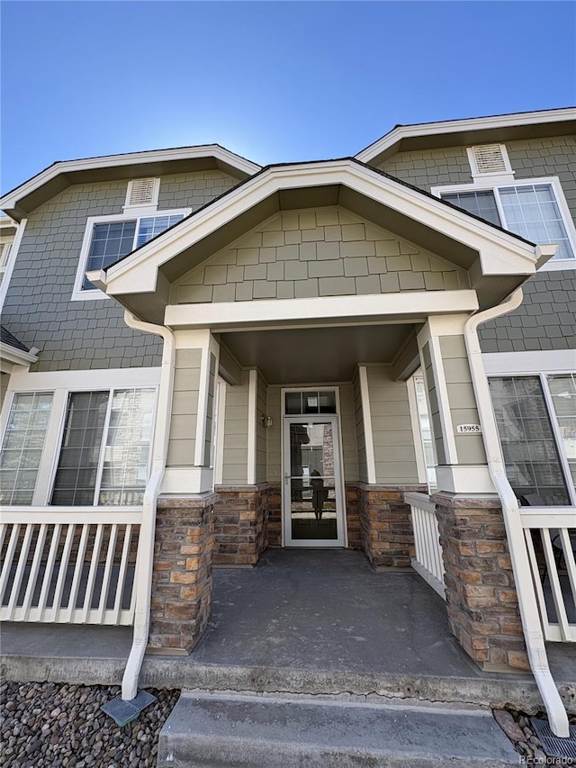 property entrance featuring stone siding and a porch