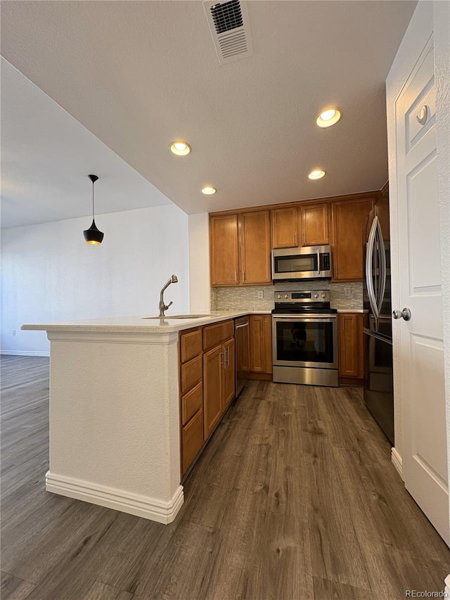 kitchen featuring visible vents, brown cabinets, a sink, appliances with stainless steel finishes, and light countertops