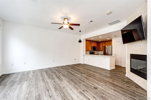 15955 E Geddes Dr Unit 55, Aurora, CO 80016 - unfurnished living room featuring wood finished floors, a ceiling fan, a tiled fireplace, baseboards, and a sink