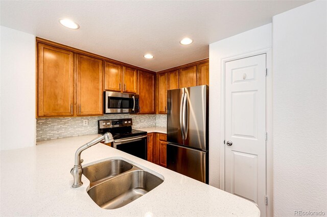 15955 E Geddes Dr Unit 55, Aurora, CO 80016 - kitchen featuring appliances with stainless steel finishes, a sink, tasteful backsplash, brown cabinetry, and recessed lighting