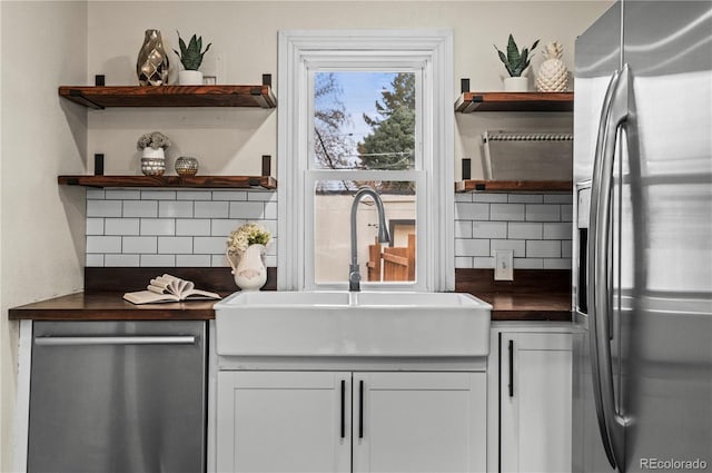 kitchen with open shelves, tasteful backsplash, appliances with stainless steel finishes, and a sink