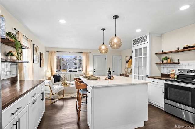 kitchen with dark wood finished floors, open shelves, stainless steel range with electric stovetop, open floor plan, and a center island