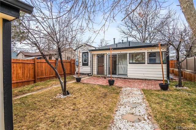 back of property with a patio, a yard, a fenced backyard, and a shingled roof