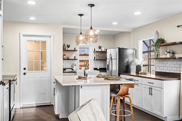 kitchen with dark wood finished floors, open shelves, hanging light fixtures, and stainless steel appliances