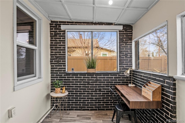 dining space with brick wall and wood finished floors