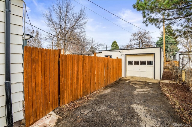 detached garage featuring driveway and fence