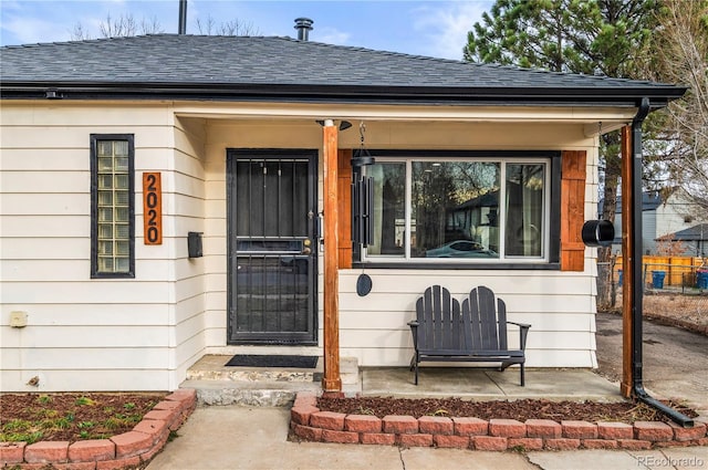 view of exterior entry with roof with shingles