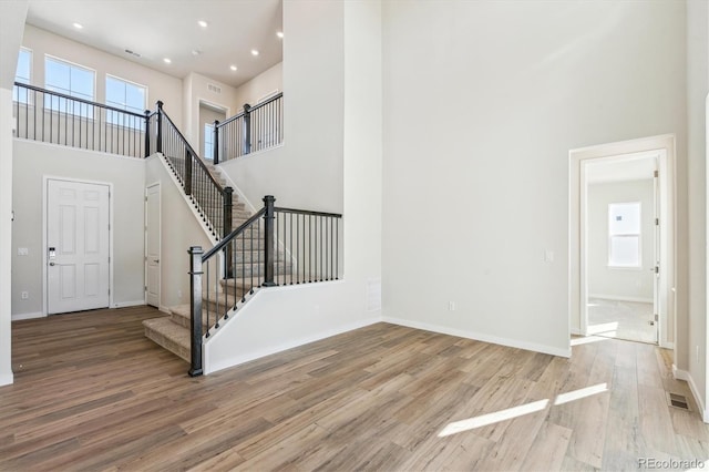 foyer with a high ceiling, a healthy amount of sunlight, and hardwood / wood-style flooring