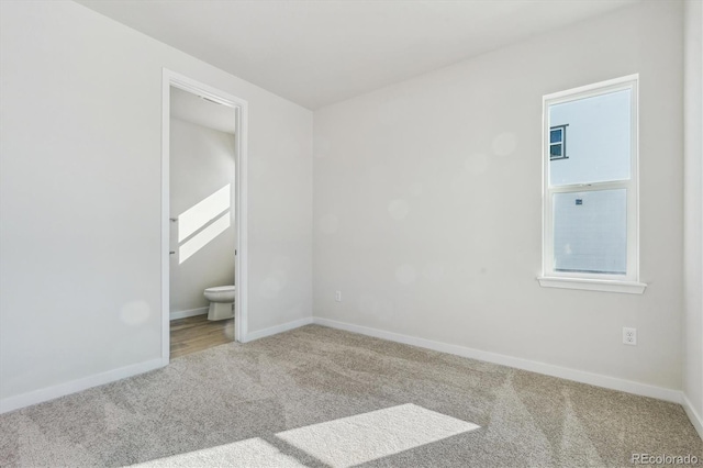 unfurnished bedroom featuring ensuite bathroom and carpet flooring