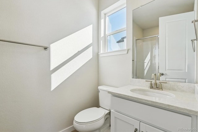 bathroom featuring vanity, toilet, and a shower with door