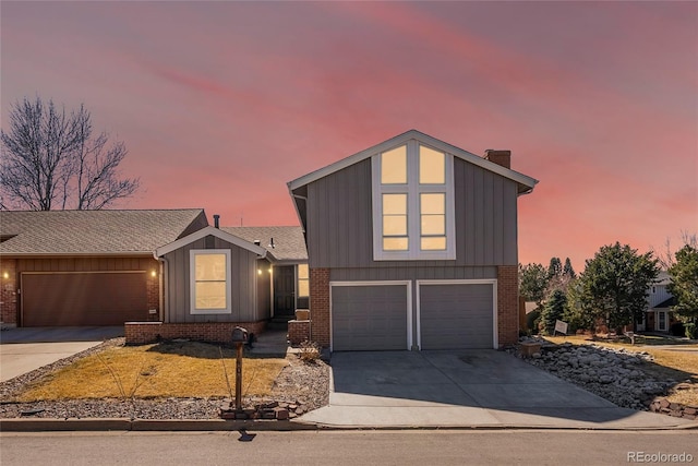 view of front facade featuring board and batten siding, concrete driveway, brick siding, and a garage