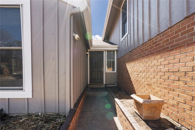 property entrance featuring board and batten siding and brick siding