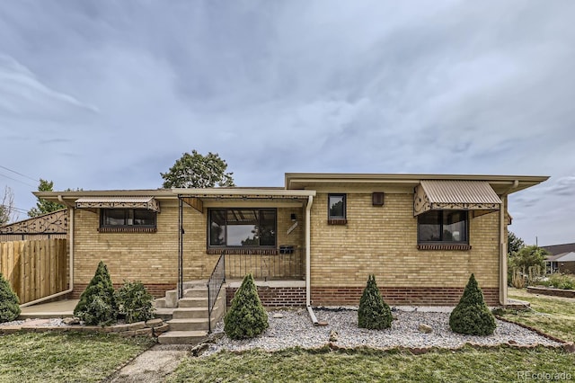 ranch-style home featuring fence and brick siding