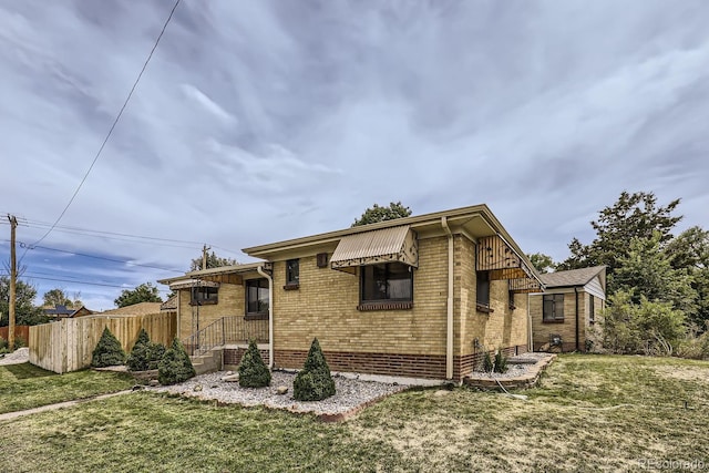 exterior space featuring brick siding, a front yard, and fence