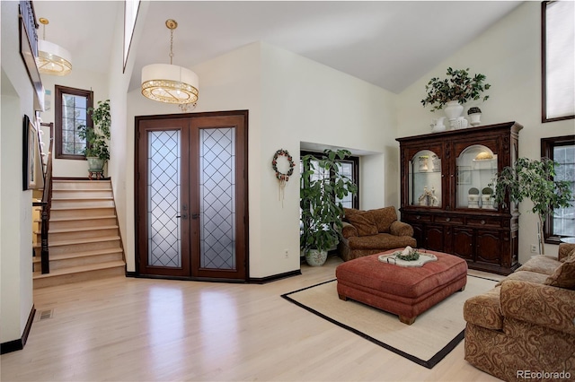 entrance foyer with high vaulted ceiling, baseboards, stairs, light wood-style floors, and french doors