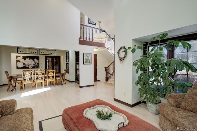 living area featuring baseboards, stairway, a high ceiling, and wood finished floors