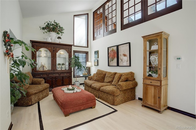 sitting room with baseboards, a high ceiling, and light wood finished floors