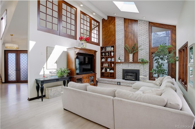 living room with a skylight, wooden walls, wood finished floors, french doors, and high vaulted ceiling