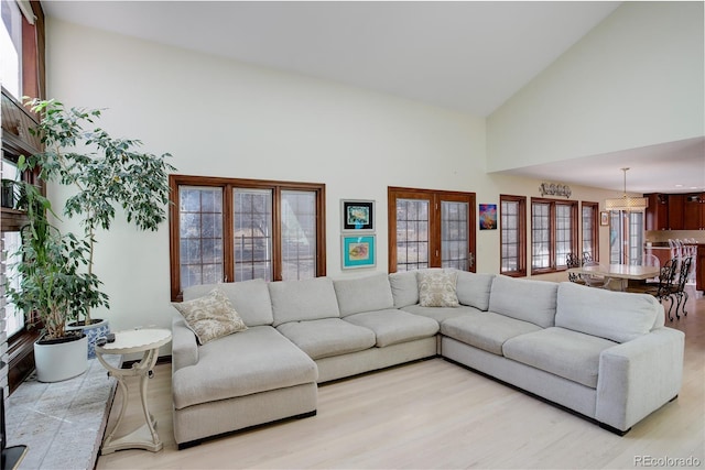 living area featuring high vaulted ceiling, french doors, and light wood-type flooring