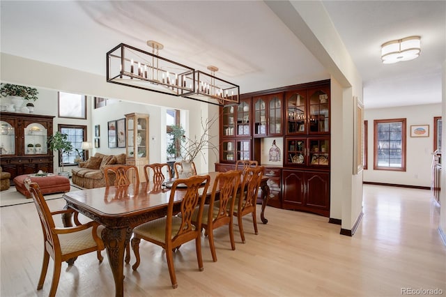 dining room featuring baseboards, light wood finished floors, and an inviting chandelier