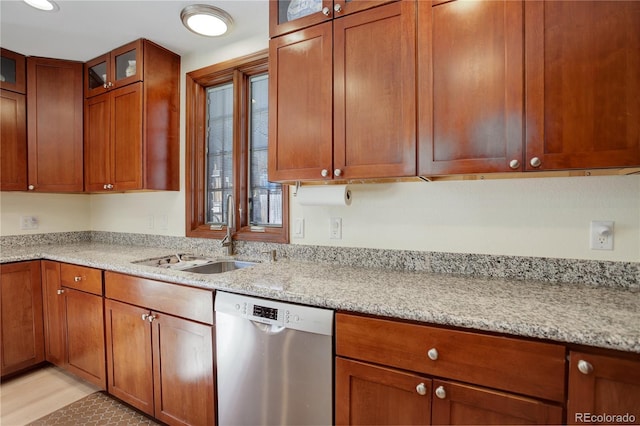 kitchen featuring light stone counters, brown cabinets, a sink, and stainless steel dishwasher