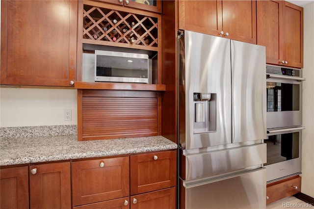 kitchen with appliances with stainless steel finishes, brown cabinets, and light stone countertops