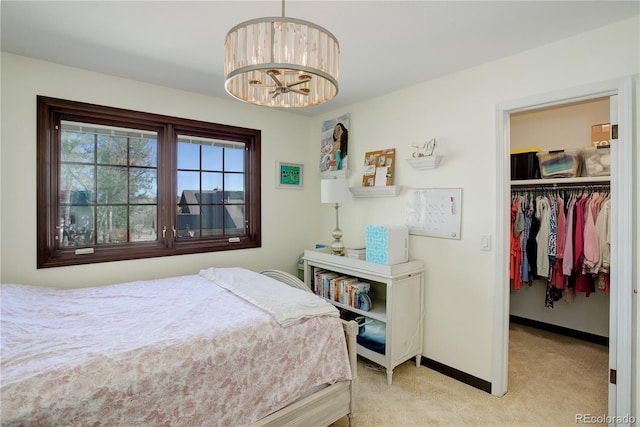 bedroom featuring a chandelier, light colored carpet, baseboards, a closet, and a walk in closet