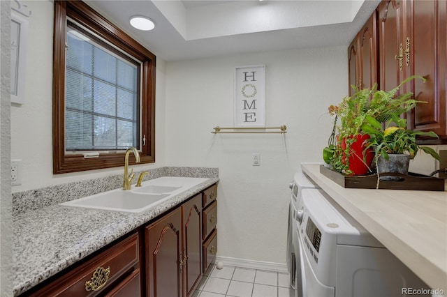 laundry room featuring light tile patterned flooring, a sink, baseboards, washer and dryer, and cabinet space